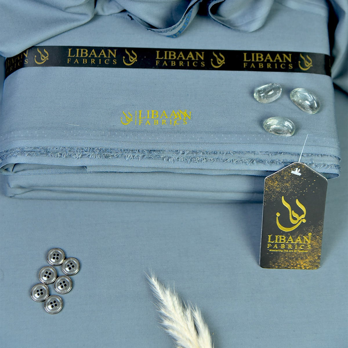 Folded fabric with 'Libaan Fabrics' branding and decorative elements on a matching background.