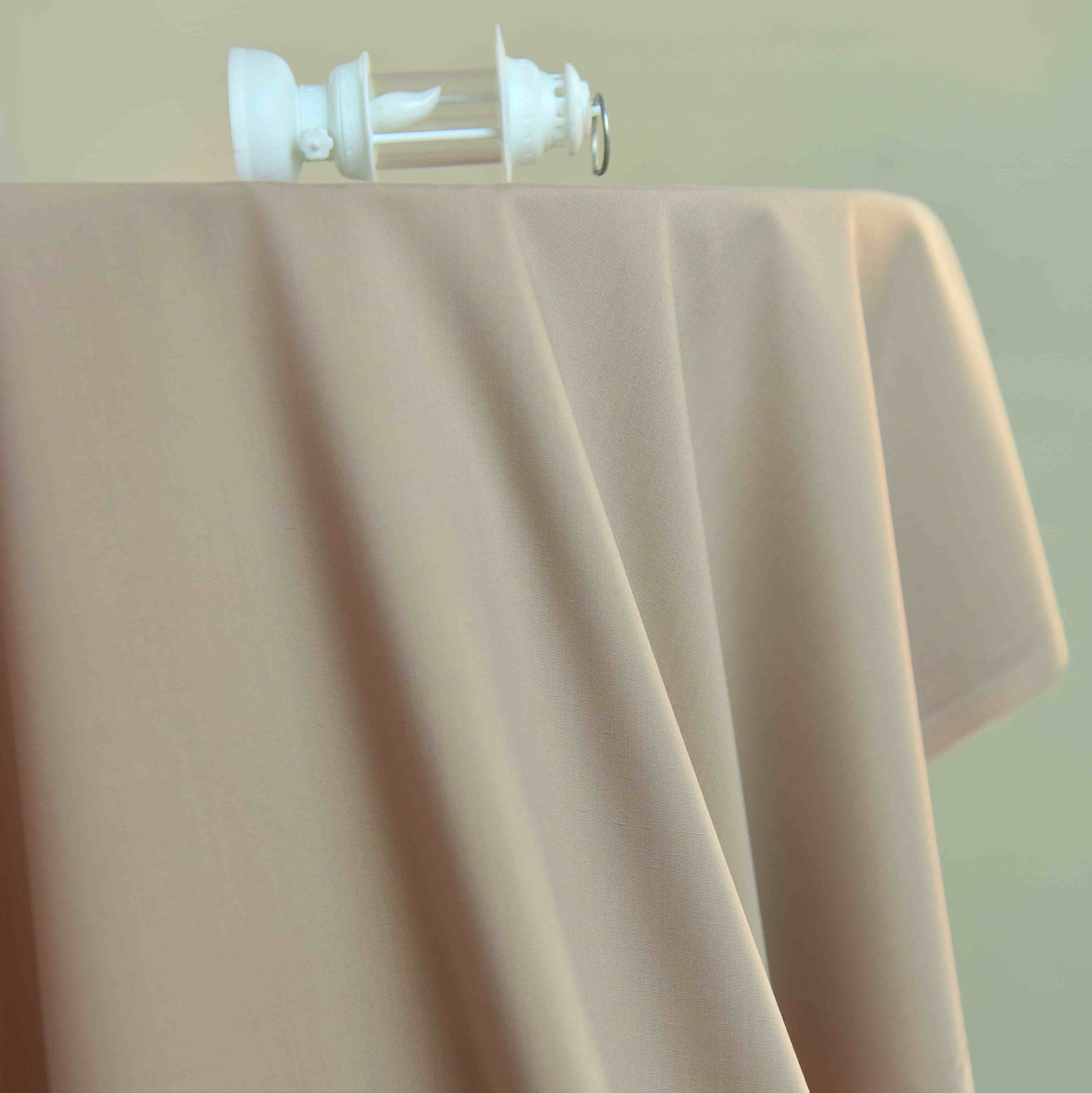 Beige fabric draped over a surface with a blurred background