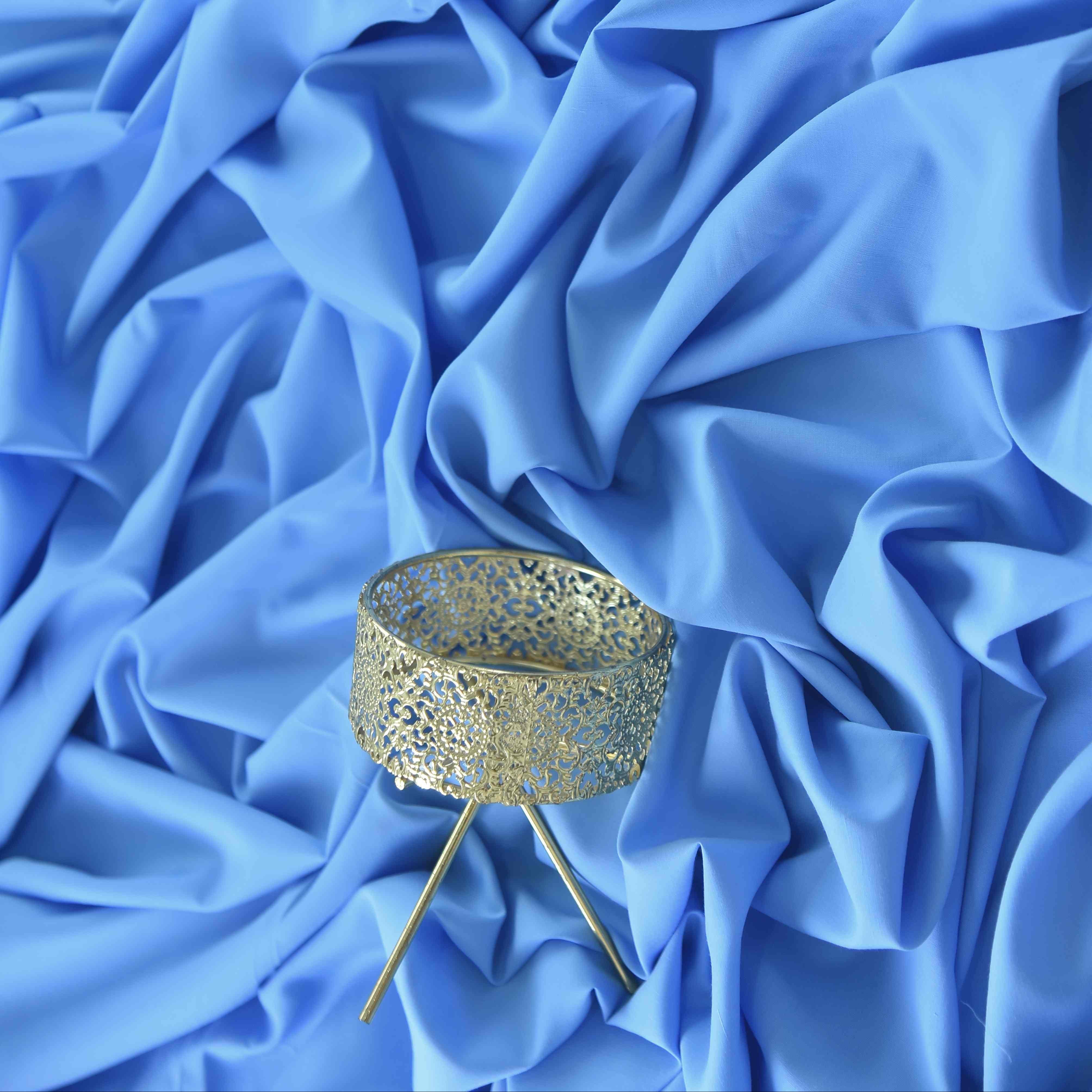Blue fabric with a decorative gold stand on a blue background